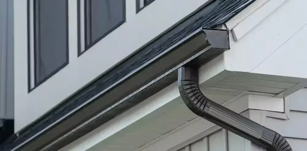 Close-up of a gutter corner where the downspout drops down the wall